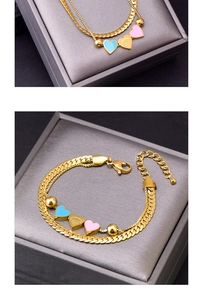 Close-up of double-layer gold snake chain bracelet with three colorful heart pendants