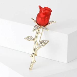 Detailed close-up of a luxury red rose brooch with gold leaves and crystal accents
