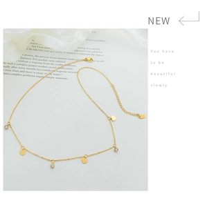 Macro detail of gold heart necklace with K18 tag and sparkling zircon accents