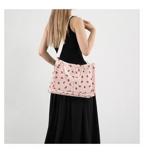 Close-up of pink corduroy tote bag with strawberry prints and dual front pockets