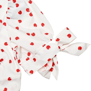Détail de la manche d'une robe d'été blanche à fleurs avec un joli nœud rouge