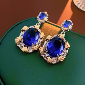 Macro shot of vintage style earrings with large blue oval stones in gold and silver frames
