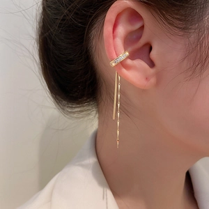 Detailed close-up of gold-plated C-shaped ear cuff with sparkling zircon and long metal tassels
