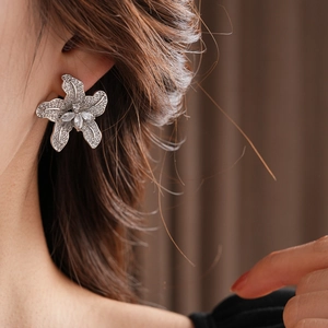 Detailaufnahme eines silbernen Blumenohrsteckers mit funkelnden Kristallen im Marquise-Schliff