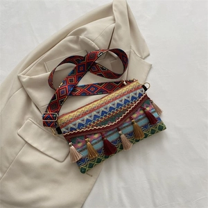 Detail of bohemian woven crossbody bag featuring colorful patterns and long hanging tassels
