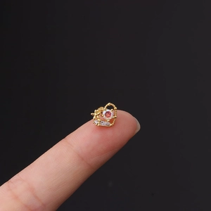 Detail of heart-shaped gold earring with opal stone and zircon held on fingertip