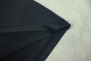 Close-up of black ruched fabric texture with fine flat-seam stitching and high-density knit