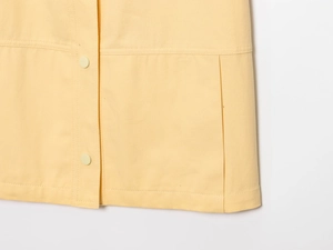 Gros plan sur les détails à deux boutons jaunes et la texture du tissu sergé