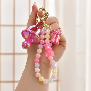 Detailed close-up of pink gradient pacifier and bottle charms on a beaded keychain