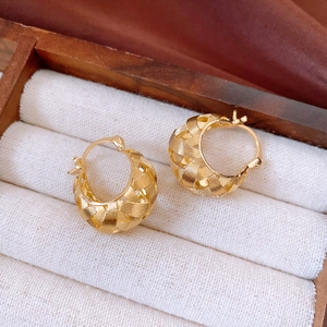 Detailed view of 18k gold plated hollow U-shaped earrings with woven texture on white fabric
