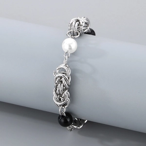 Detail of silver chain link bracelet with white pearl and black beads on display