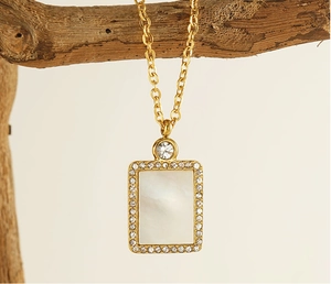 Detail of gold shell pendant with pave crystal border hanging on wood branch