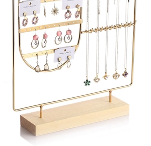 Close-up of golden iron jewelry rack with wooden base holding earrings and necklaces