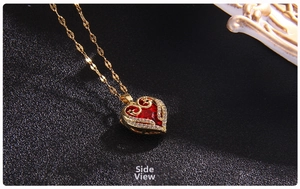 Side view detail of a gold heart necklace with a large red crystal and white diamonds