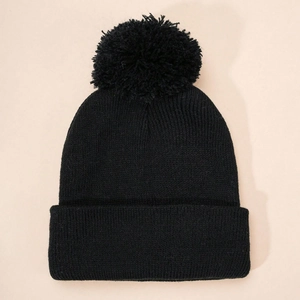 Close-up of black ribbed knit beanie featuring a large pom-pom and folded cuff detail