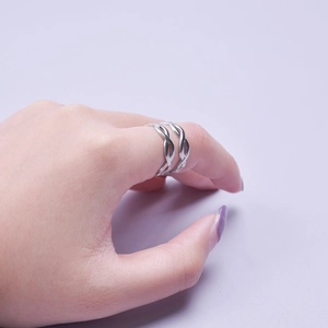 Silver infinity double twist adjustable ring on hand with light purple background