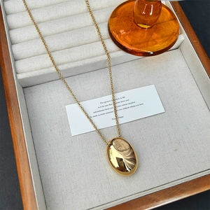 Detail of a golden waterdrop pendant necklace resting in a premium wooden jewelry box