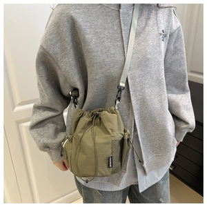 Detail of army green nylon bucket bag featuring drawstring closure and side mesh pocket