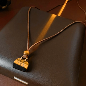 Macro shot of tiger eye stone handbag pendant on brown leather cord necklace