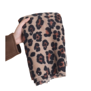 Winter leopard print cashmere scarf with tassel trim shown held in hand against white