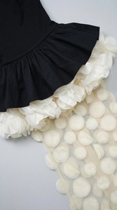 Detailed close-up of 3D white floral texture and black contrast hem on evening dress