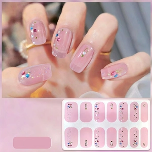 Detailed view of 5D pink gel nail stickers with gold accents and colorful rhinestones