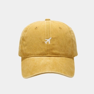 Detailed view of the fine white airplane embroidery on a yellow cotton baseball cap