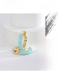 Close-up of gold-plated hoop earrings with mint green enamel on geometric pedestals