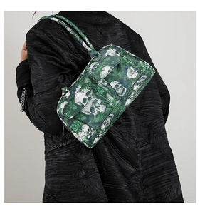 Detail of green floral skull print shoulder bag worn with a black textured coat