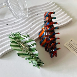 Large acetate hair claws in colorful stripes and green patterns on a white tray