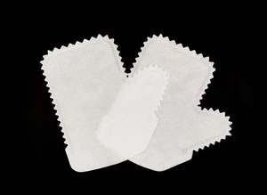 Macro detail of white non-woven cleaning gloves with jagged edges on black background