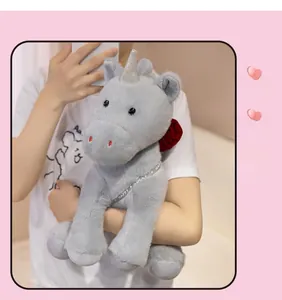 Detail of grey plush unicorn toy with silver horn and deep red rose on the back