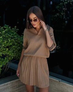 Détail du haut polo en maille camel et jupe plissée montrant la texture et les rayures