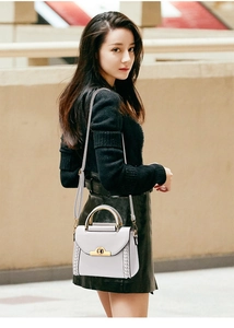 Close-up of leather handbag with metal handle, gold twist lock and woven texture