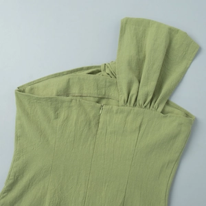 Detail view of the green cotton dress showing the hidden zipper and ruching on the shoulder