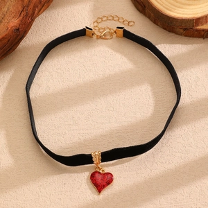Dettaglio di un girocollo nero con cuore glitterato rosso e finiture dorate di lusso