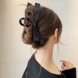 Detail of elegant black satin bow hair claw clip styled in a sophisticated updo for women