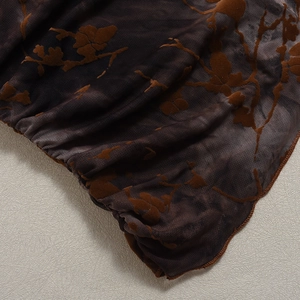Close-up of dark brown sheer mesh fabric with floral flocking detail and textured drapes