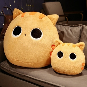 Dettaglio di due morbidi cuscini di peluche a forma di gatto arancione su un divano