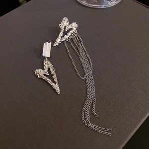 Detailed macro view of asymmetric silver heart earrings with long fringe tassels