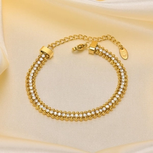 Detail of double-layer gold-plated bracelet with white zircons on champagne silk background