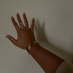 Minimalist wavy stainless steel rings and gold pearl bracelet set on hand