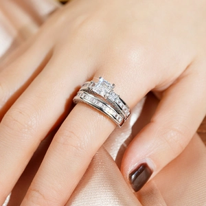 Detailopname van de zilveren dubbele ringenset met prinsesgeslepen steen op zijde