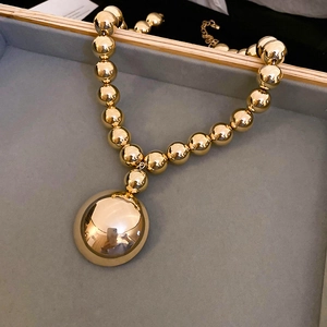Macro shot of chunky gold beaded necklace with large polished pendant in display case