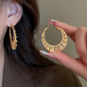 Detailed close-up of chunky gold-plated braided hoop earrings with woven texture