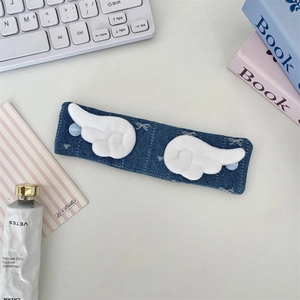 Detail of blue denim cable organizer with white plush wings on a white office desk