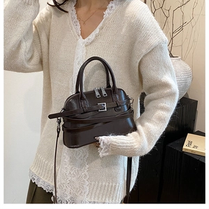 Close-up of dark brown leather shell bag with silver hardware and adjustable strap