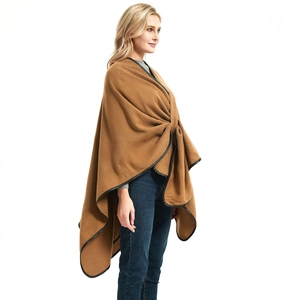 Elegant camel knit shawl with black leather trim and fringe tassels on a fashion model