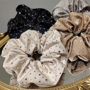 Close-up of sparkling rhinestone-embellished satin scrunchies in multiple elegant colors