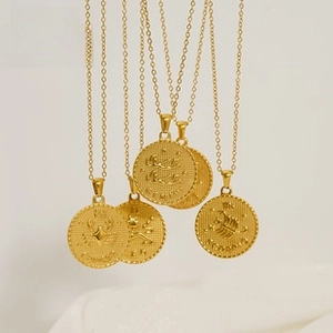 Detailed macro view of gold-plated stainless steel coin necklaces with zodiac engravings